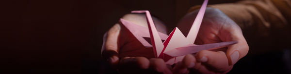 a paper crane sitting on top of open palms