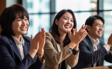 a group of three people happily applausing in a meeting room